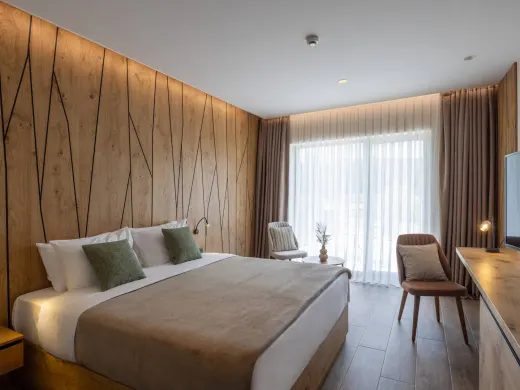 Helles Doppelzimmer in der Alpensaline mit Holzwand, Doppelbett und großem Fenster