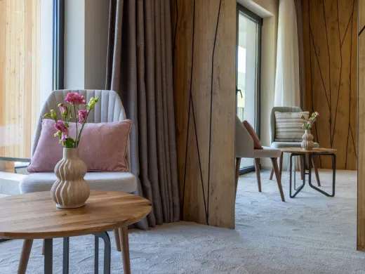 Sitzbereich mit Sessel, Tisch und Spiegel im Doppelzimmer